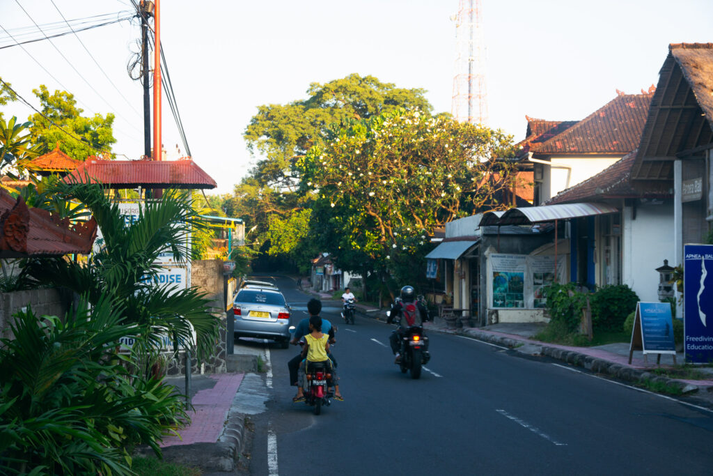 A typical street scene in Bali, with motorcyclists and a car on a paved road