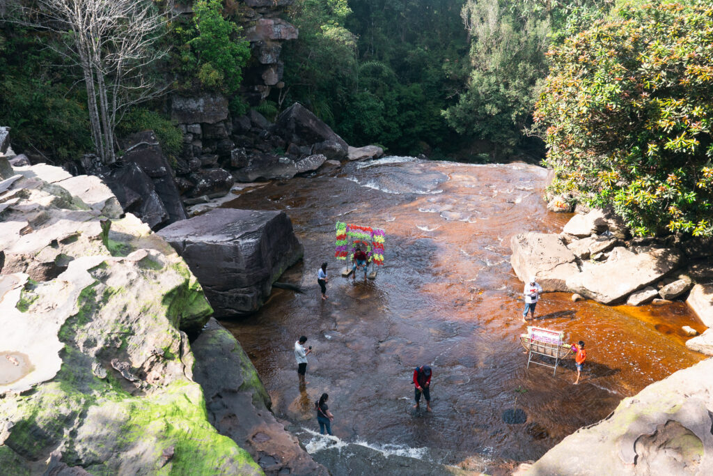 Overhead view of people in a shallow river with large boulders in Popokvil Waterfall