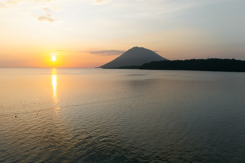 Sunset over Bunaken Island with orange sky and mountain in the background
