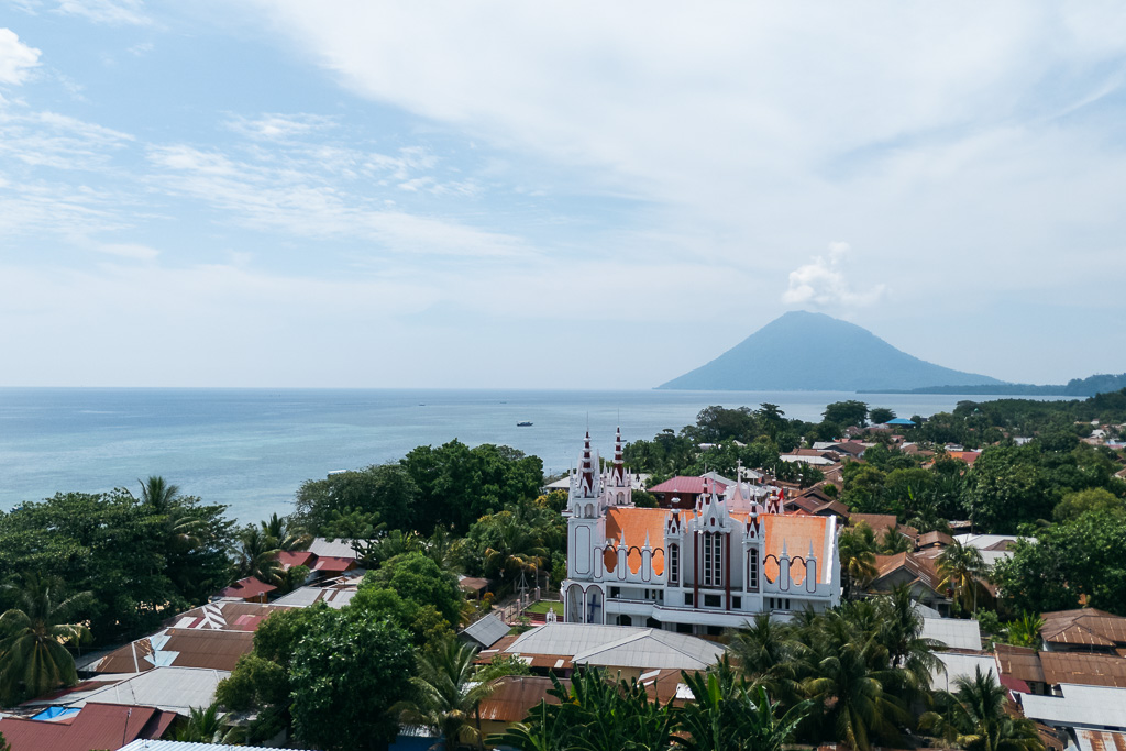 Elevated view of Bunaken Island town with a mountain and ocean backdrop