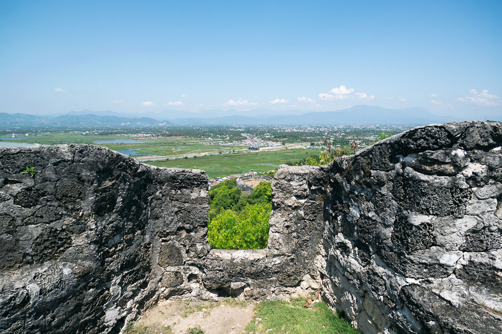 View from inside Benteng Otanaha’s stone walls overlooking wetlands, a town, and distant mountains