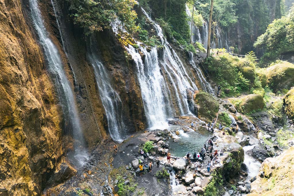 A majestic view of a multi-tiered waterfall cascading down a rocky, moss-covered cliff face