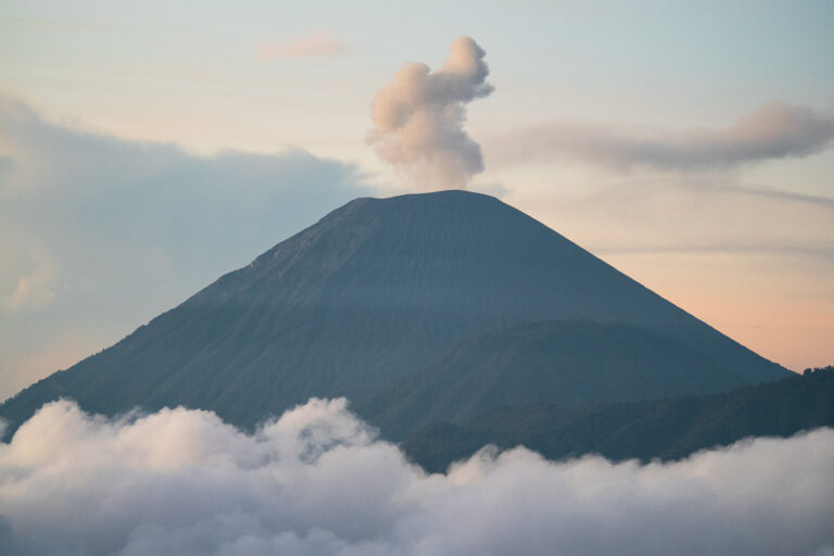 Mount Bromo emitting smoke, surrounded by clouds
