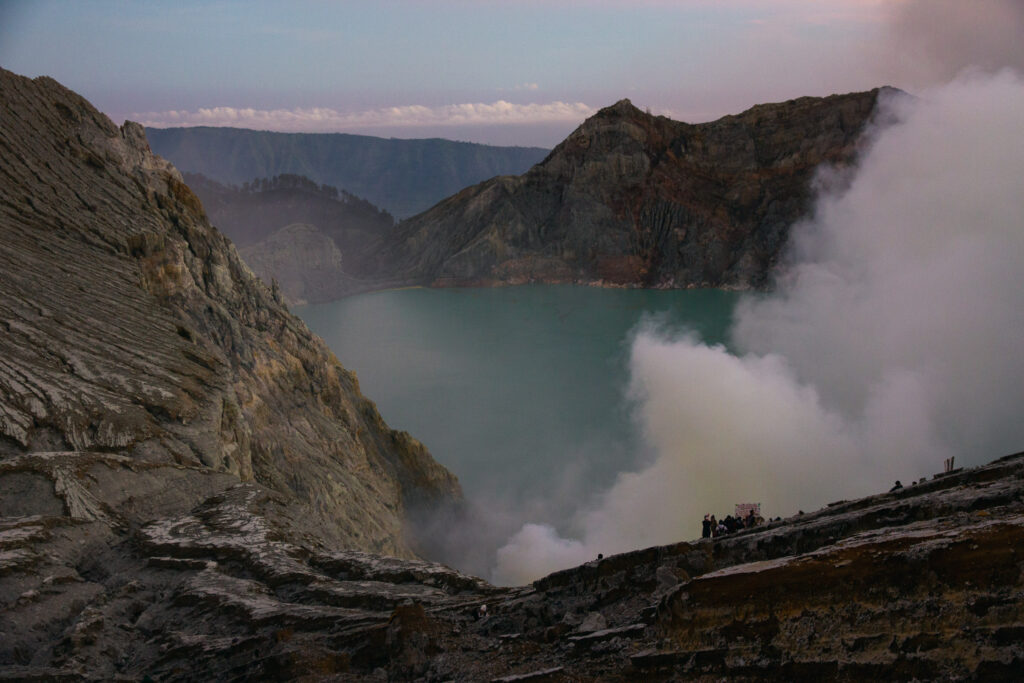 Mount Ijen crater lake with smoke and rocky slopes