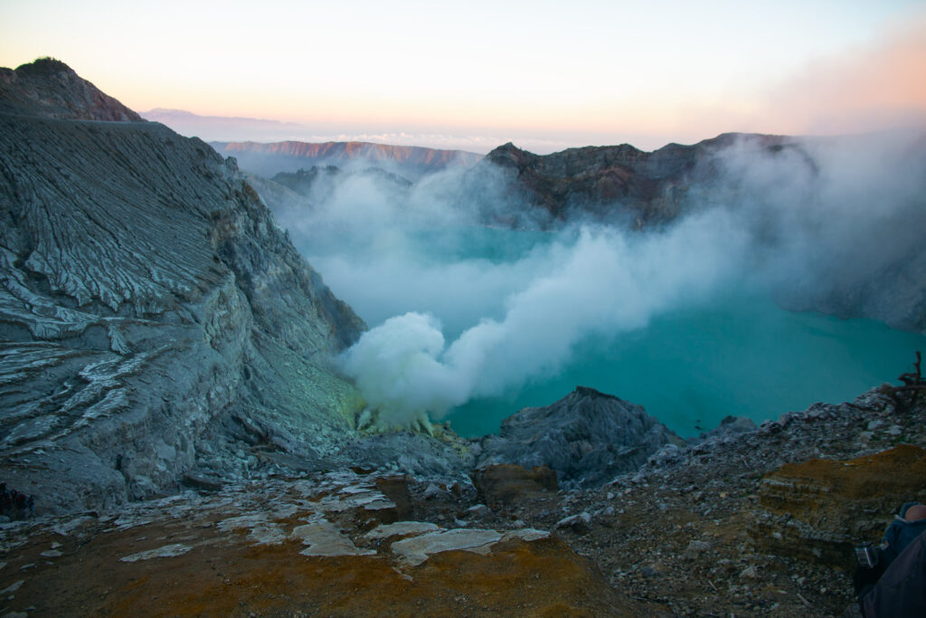 Mount Ijen crater lake with smoke and rocky slopes