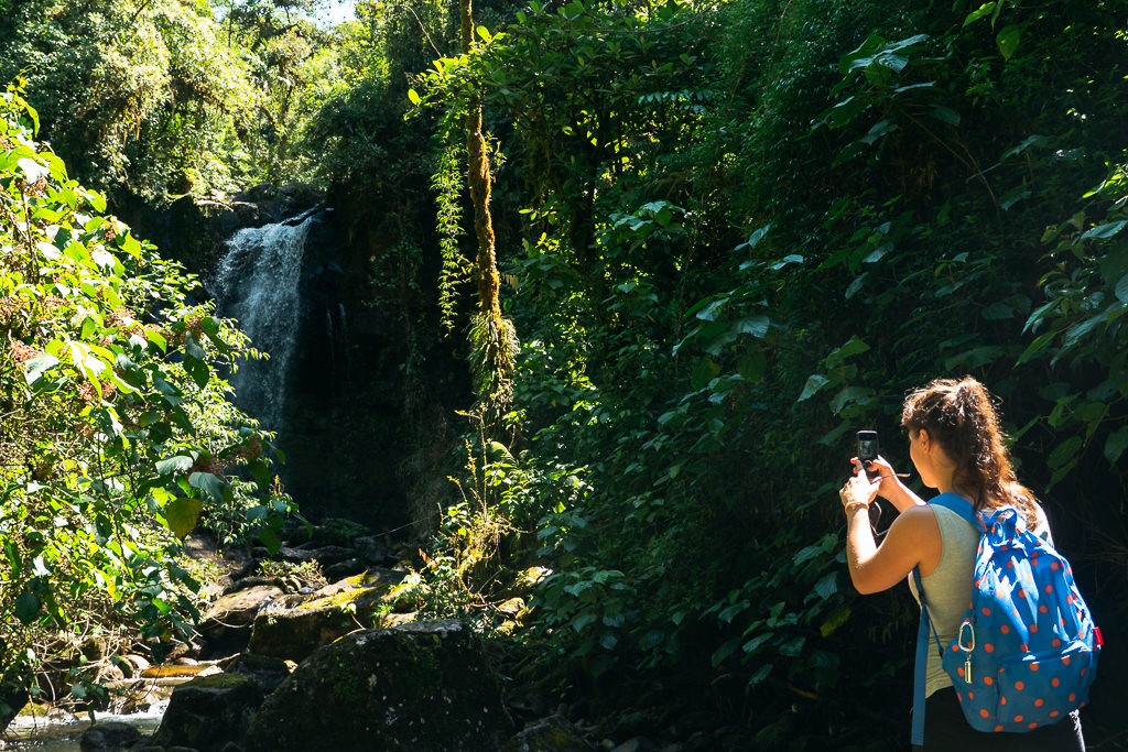 A woman taking a picture of a waterfall in Boquete, Panama.