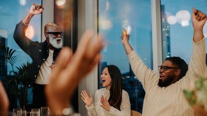 Office workers celebrate in a conference room.