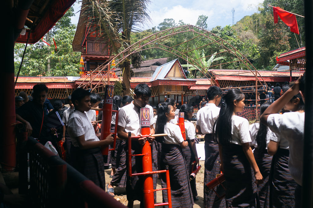 Group of youth in traditional attire gathered with red drums in Tana Toraja